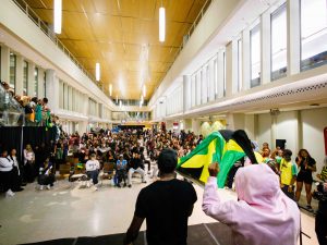 People on stage look out over a crowded audience at a Black History Month event at a university.