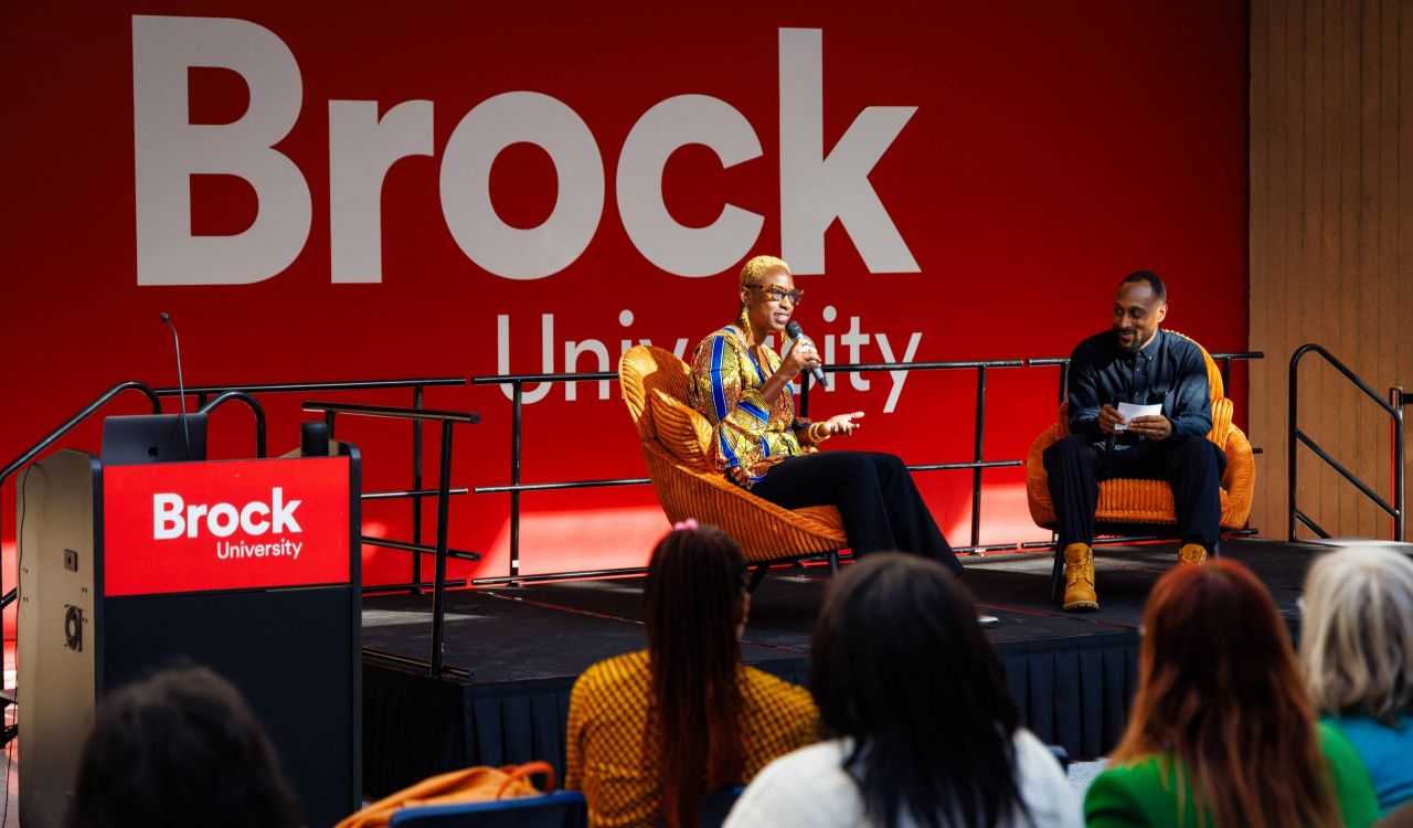 Two people have a conversation on stage during an event.