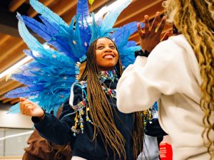 A smiling person wears a carnivale headdress.