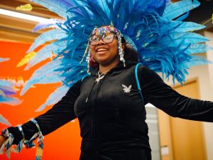 A smiling person wears a carnivale headdress.