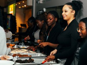 A group of people serve themselves food from a buffet table.