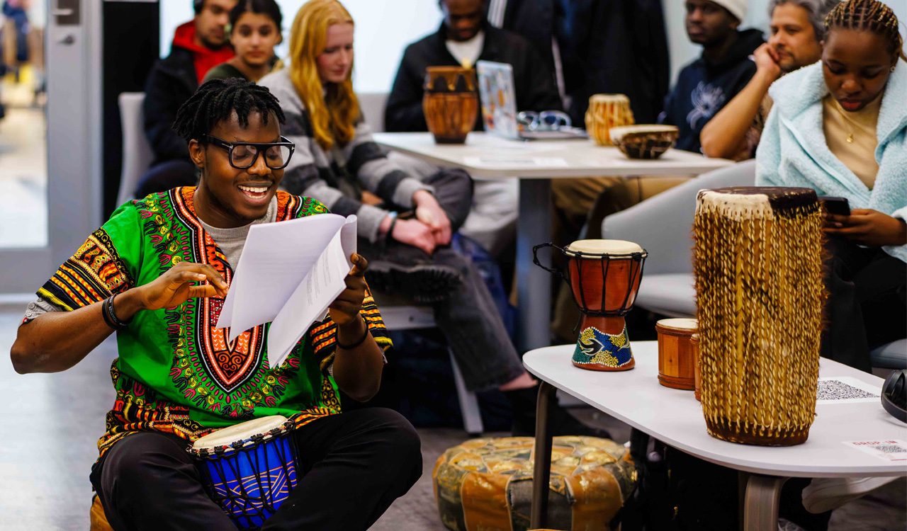 A young man plays a traditional drum during a Black History Month/African Heritage Month event.