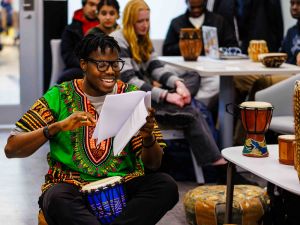 A young man plays a traditional drum during a Black History Month/African Heritage Month event.