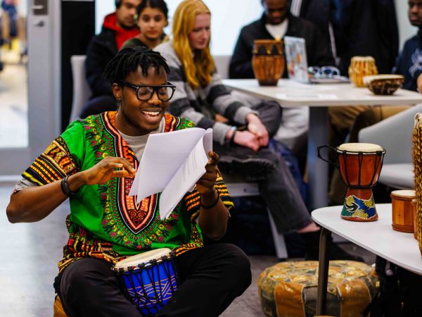 A young man plays a traditional drum during a Black History Month/African Heritage Month event.