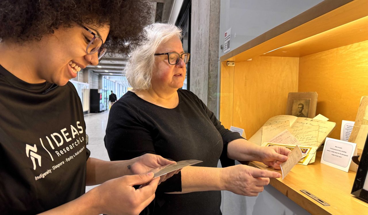 Two women look at photographs in a display case.
