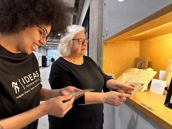 Two women look at photographs in a display case.