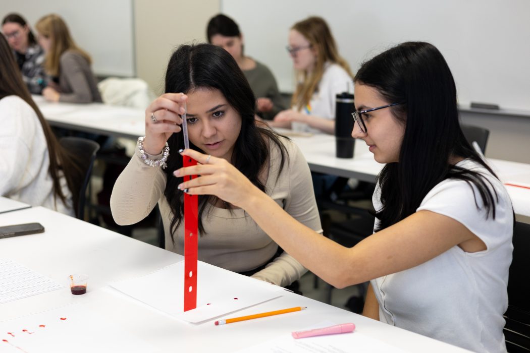 Two university students work with a fake blood in a criminology workshop.