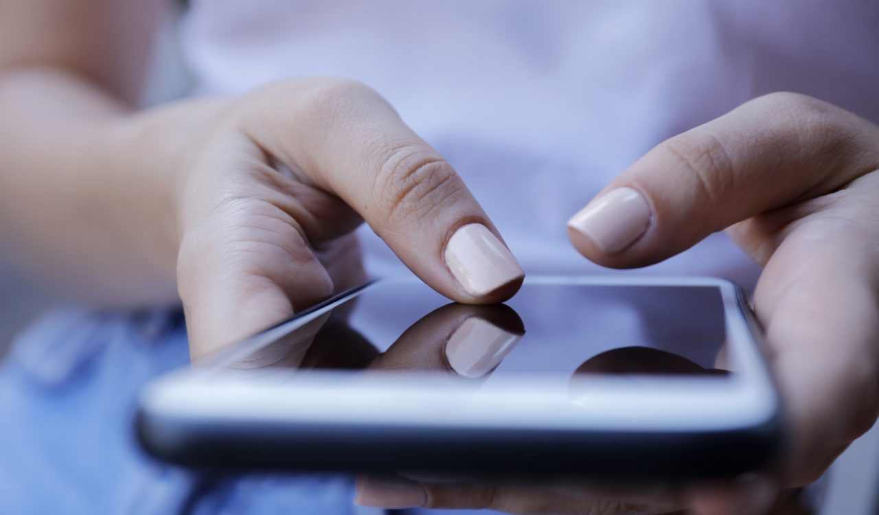 Close-up of hands typing on a phone.