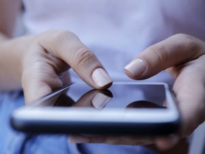 Close-up of hands typing on a phone.