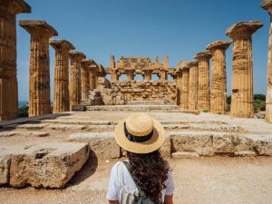 A woman, seen from behind, looks at ancient ruins.