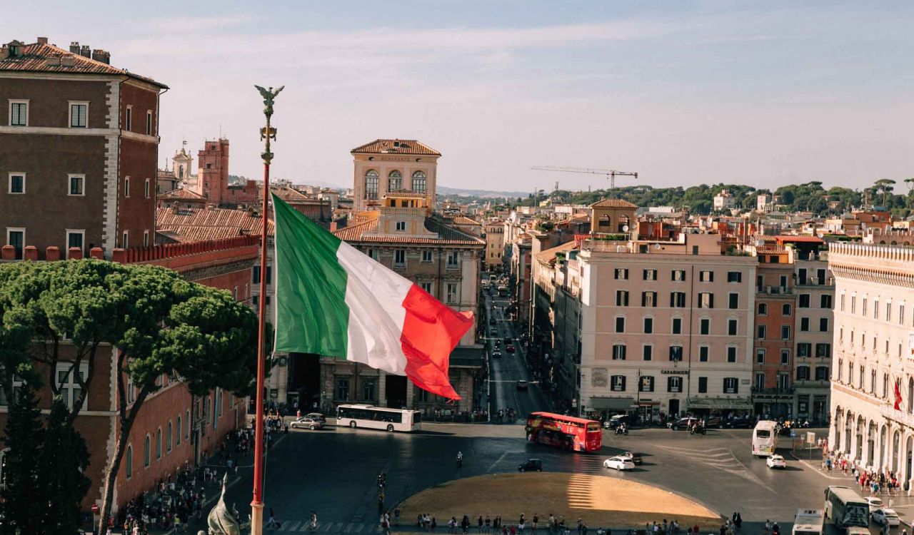 A view of the Italian flag with the city of Rome in the background.