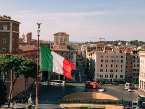 A view of the Italian flag with the city of Rome in the background.