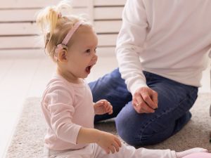 A baby with cochlear implants plays in the living room of their home.