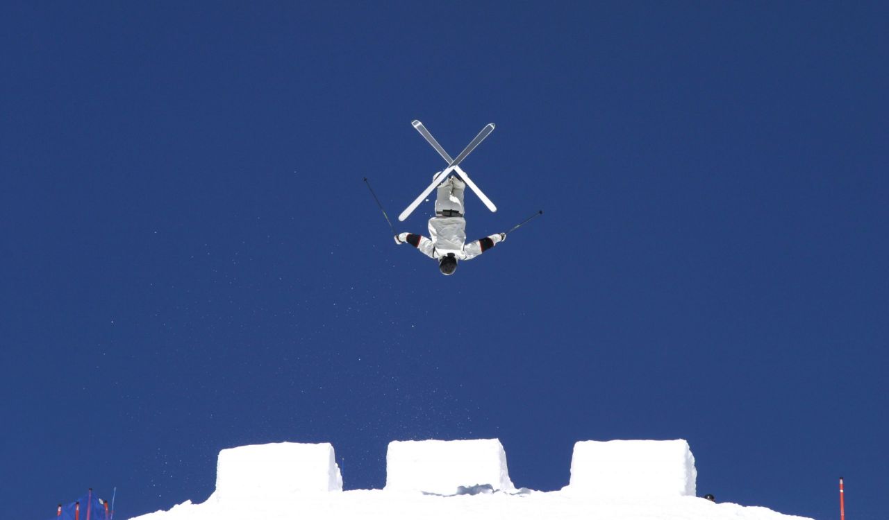 A person in skis jumps off a ramp.