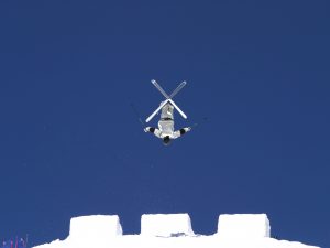 A person in skis jumps off a ramp.