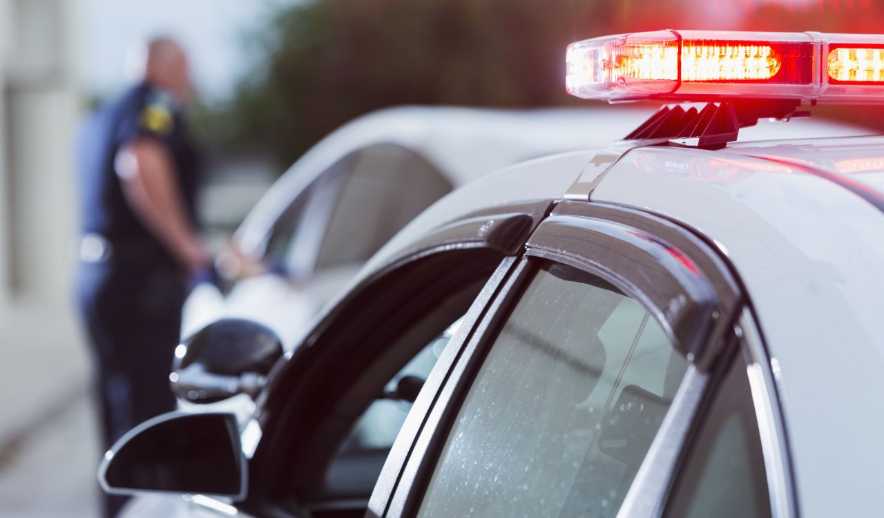 A police officer stands next to a car he pulled over.