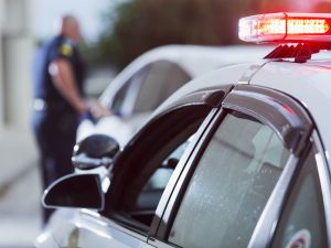 A police officer stands next to a car he pulled over.