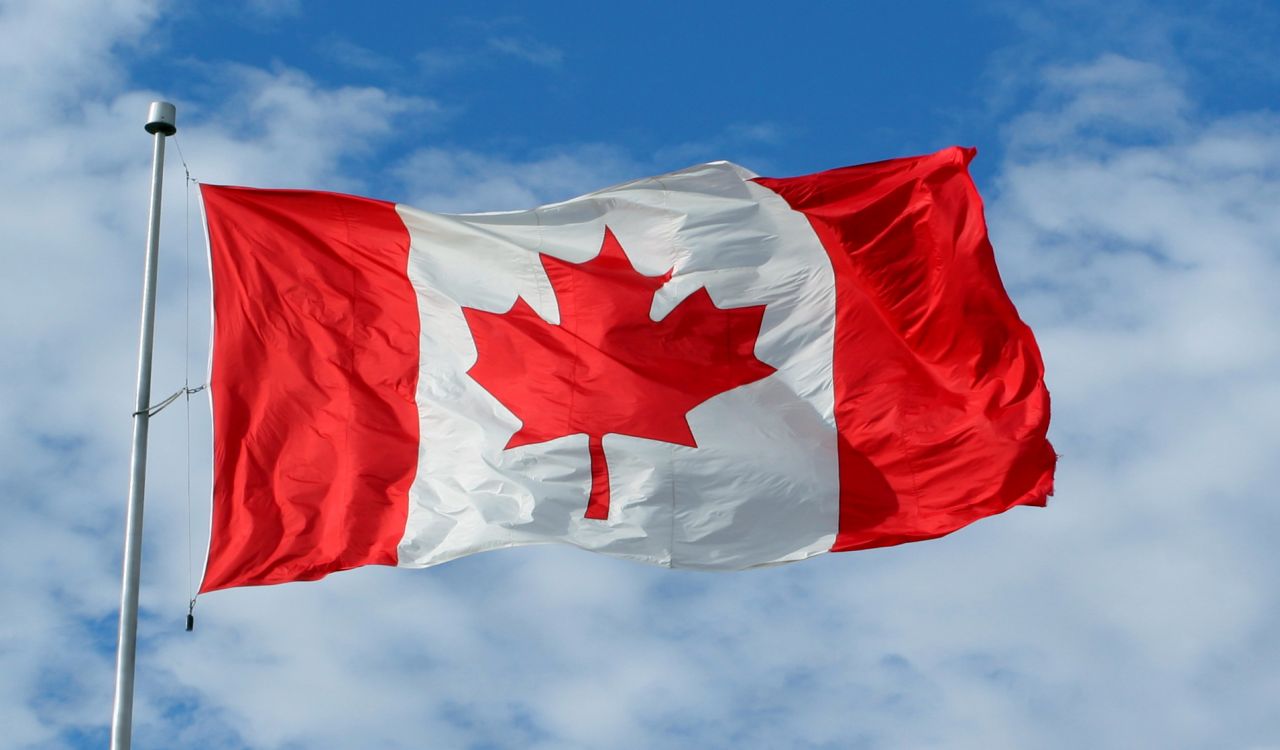 Canada's national flag flying against a blue sky.