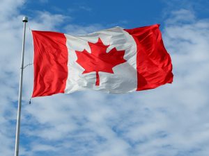 Canada's national flag flying against a blue sky.