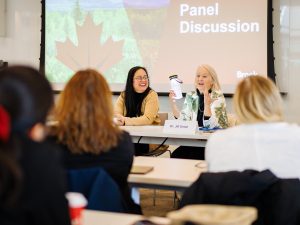 Jill Grose addresses the audience while holding up a water bottle which includes a light during a panel discussion.