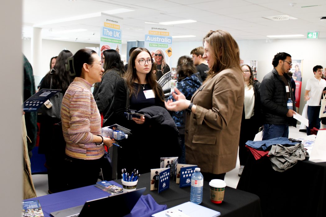 Three people have a conversation in a busy room.