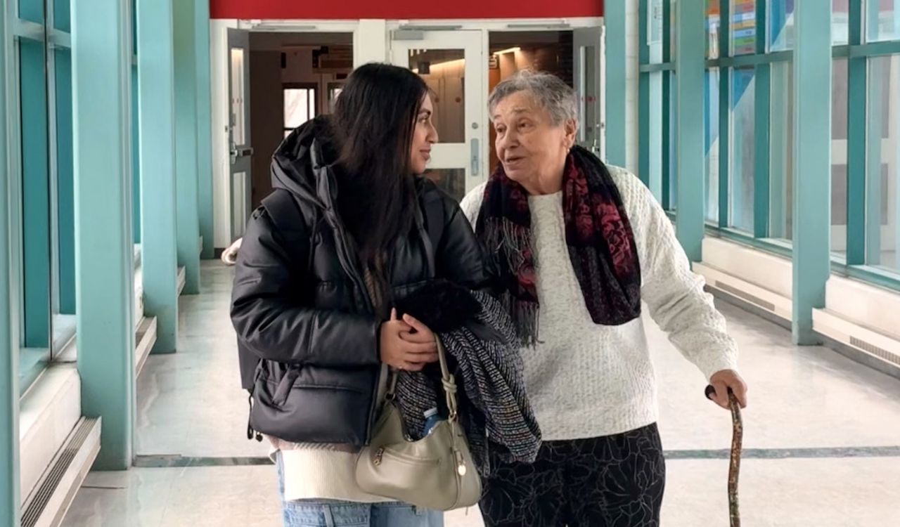 A young woman and an older woman walk down a hallway together.