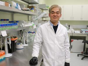 A man in a lab coat stands in a lab.