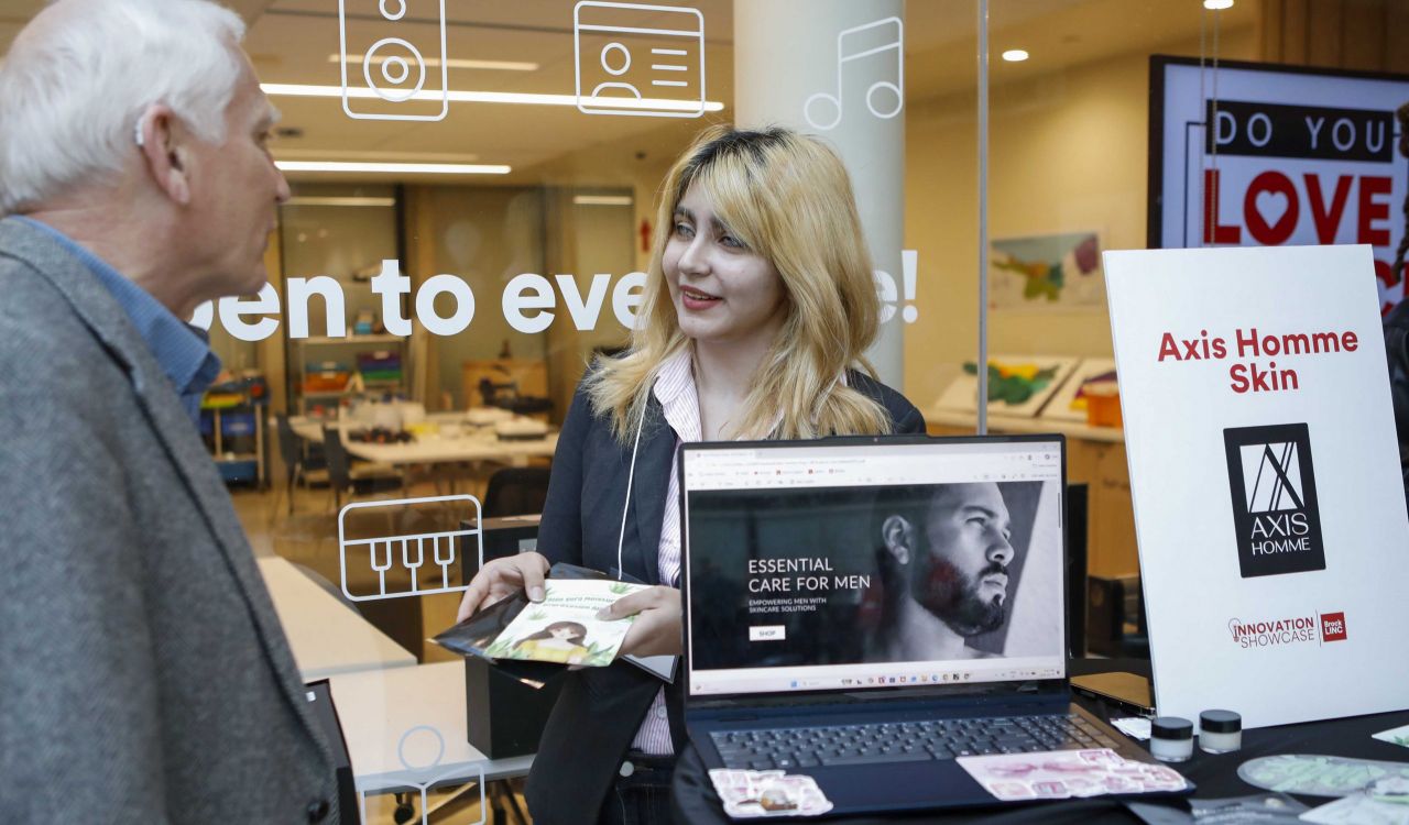 A young woman shares promotional material with a man during an entrepreneur fair.