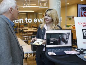 A young woman shares promotional material with a man during an entrepreneur fair.