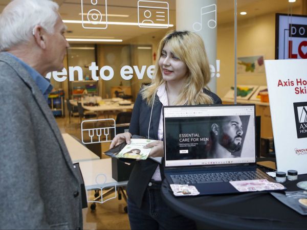 A young woman shares promotional material with a man during an entrepreneur fair.