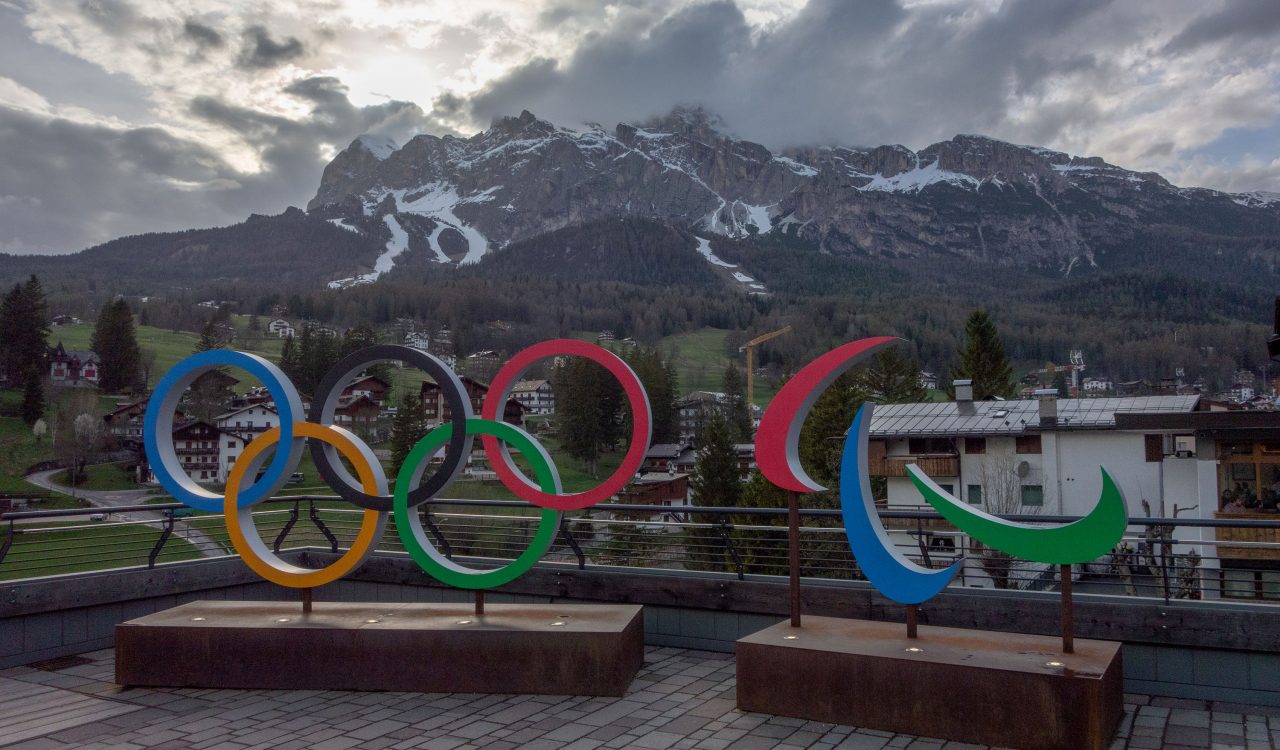 The Olympic rings stand before a picturesque mountain range.