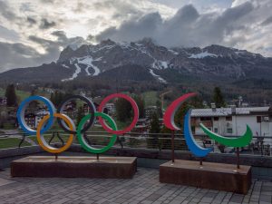 The Olympic rings stand before a picturesque mountain range.