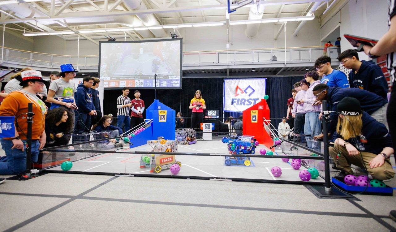 Teams of high school students compete at a robotics competition.