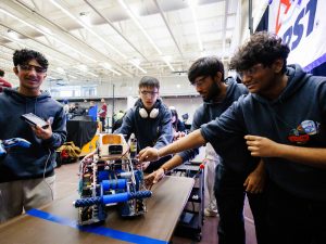 High school students work on a robot during a robotics competition.