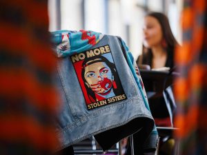 A denim jacket draped over a chair displays a patch reading “No More Stolen Sisters” during the REDress Day event.