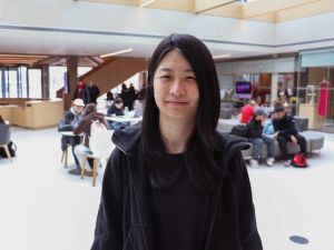 Portrait of computer Science student Jiani Zhao, with people sitting at tables and on chairs in the background.