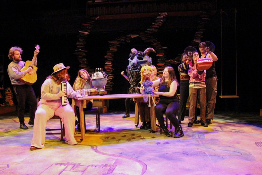 A group of actors stand on a stage performing a play.