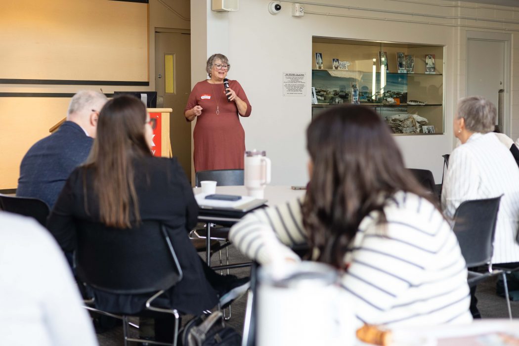 A woman speaks to an audience from a podium.