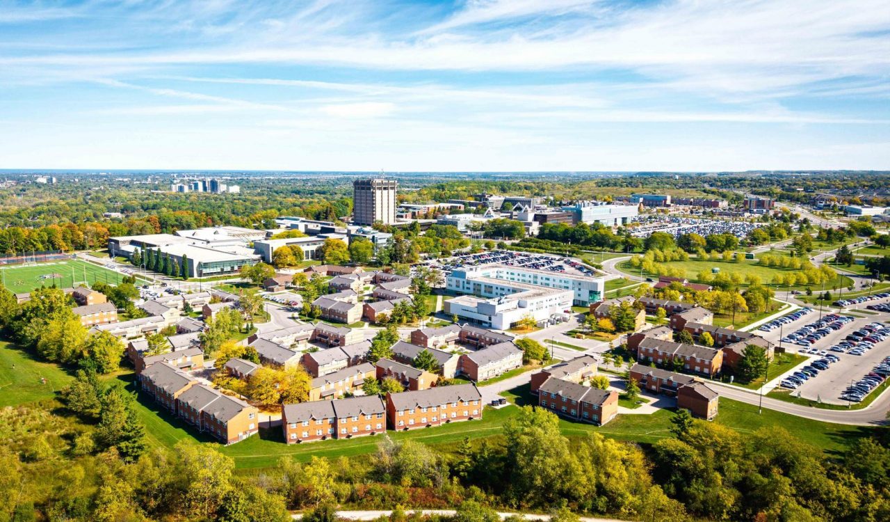 A wide view of Brock University’s main campus, featuring modern campus buildings beneath a bright blue sky.