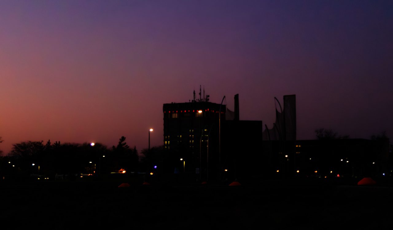 Nighttime image of Brock University with low lighting and purple and pink sky.
