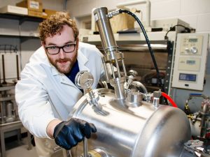 A man in a lab coat works with research equipment.