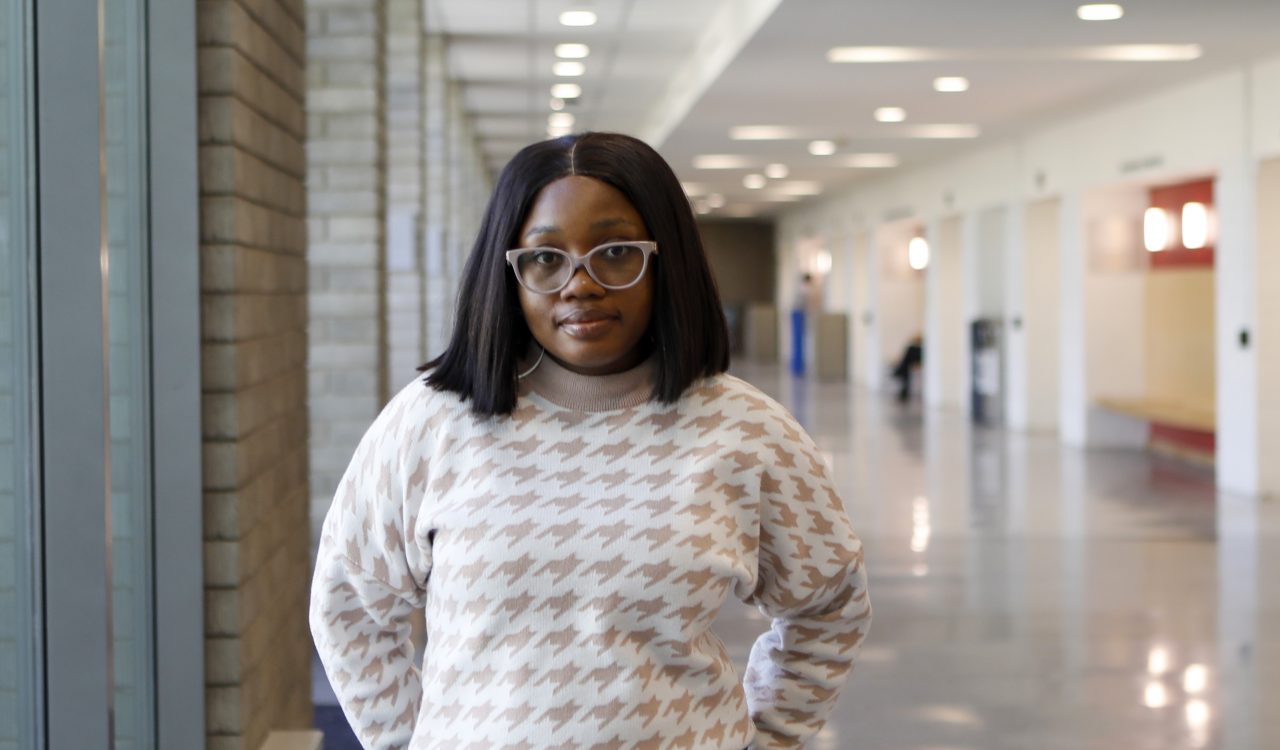 A woman is standing in a hallway of a university building.