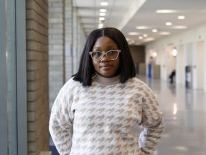 A woman is standing in a hallway of a university building.