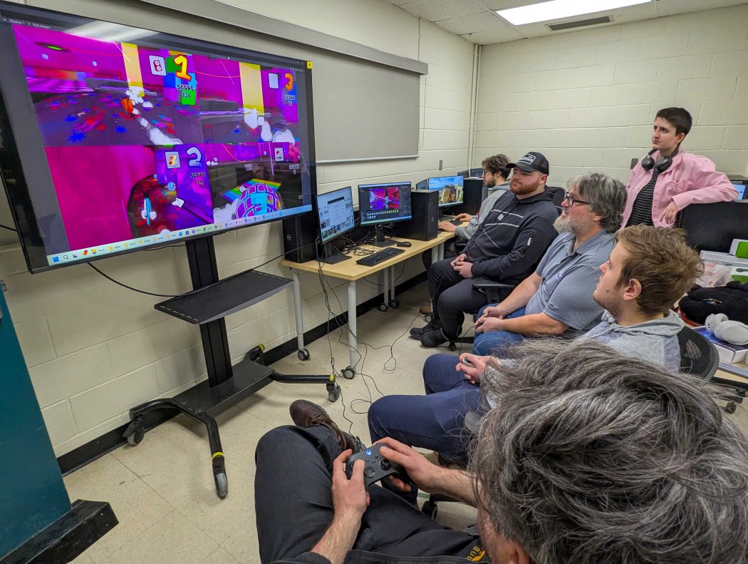 A group of people play a video game on a big TV.