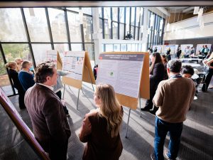 A group of people look at research posters at an academic conference.