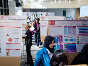 A group of people look at research posters at an academic conference.