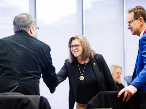 Two people shake hands at a business event.