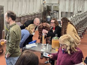 A group of people stand in a fermentation science lab looking at cider samples.