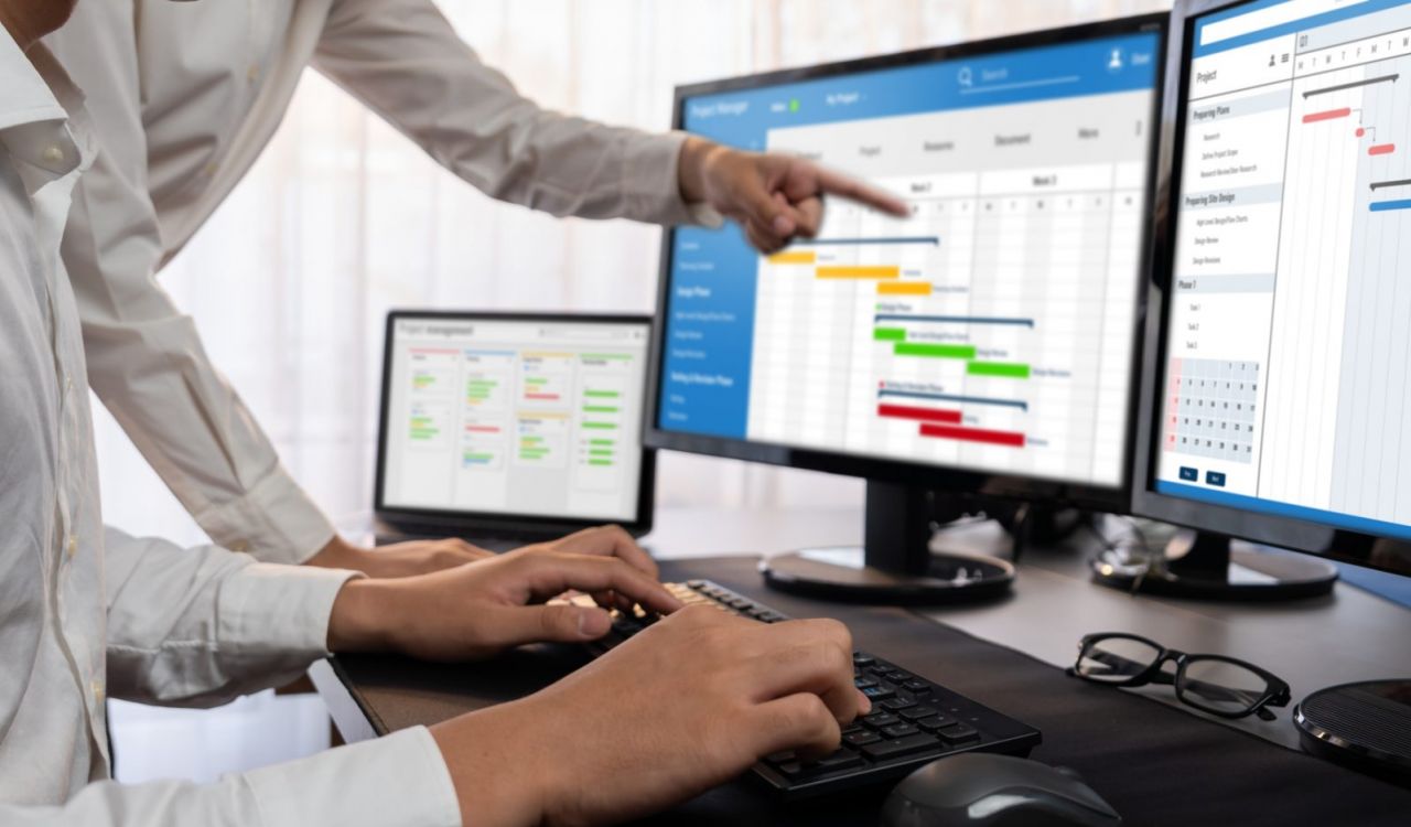 Close-up of people in an office working on charts, which can be seen on three screens.
