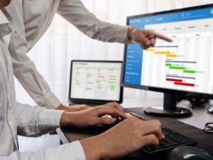Close-up of people in an office working on charts, which can be seen on three screens.